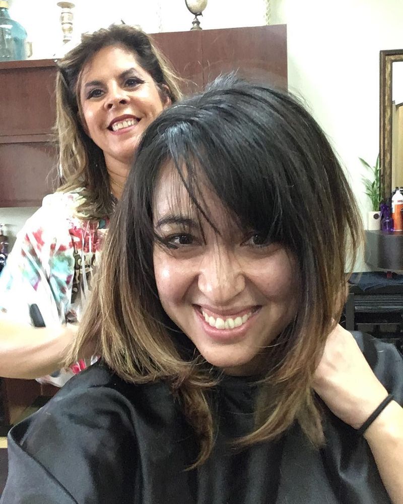 A smiling client showing her new balayage bob while Maria smiles behind her