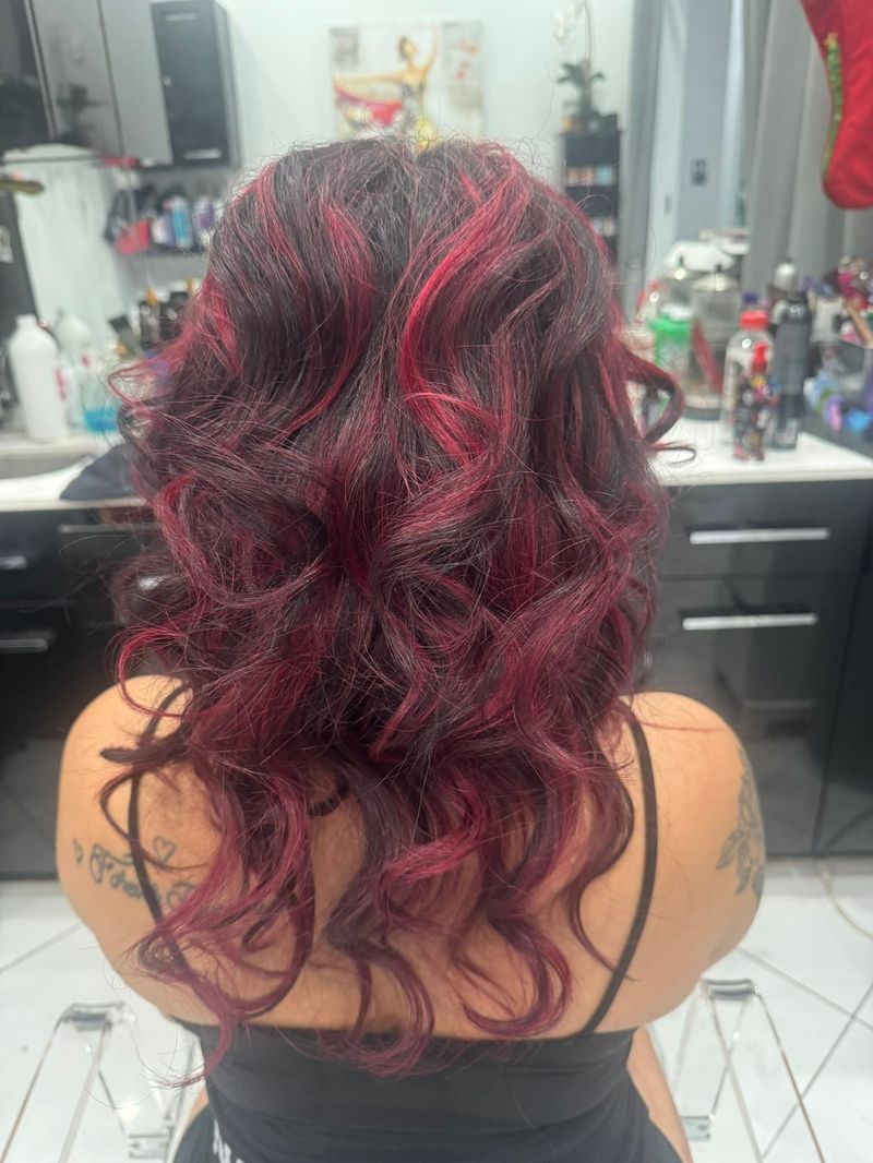 Back view of a client's long hair in rich red and burgundy waves, colored by Maria